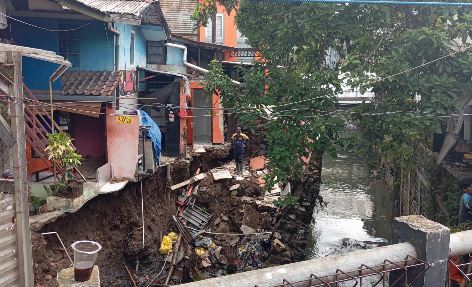 Seorang petugas tengah mengevakuasi sejumlah material bangunan di sekitar rumah terdampak saluran kirmir jebol, Kelurahan Arjuna, Kecamatan Cicendo, Kota Bandung, pada Senin (18/11). (NIZAR/JABAR EKSPRES)