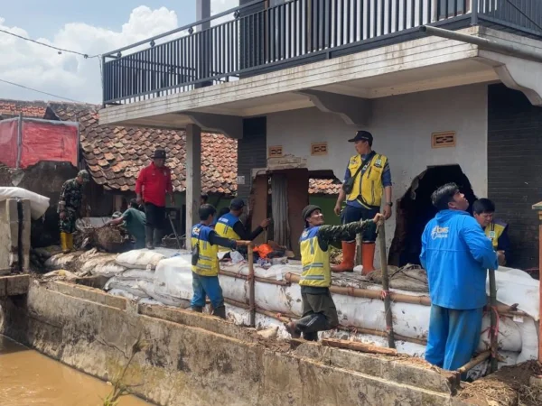 Petugas saat memperbaiki tanggul yang jebol di dekat rumah Noval yang hancur oleh aliran deras sungai. (Agi / Jabar Ekspres)