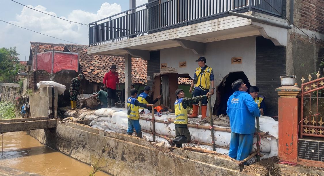 Petugas saat memperbaiki tanggul yang jebol di dekat rumah Noval yang hancur oleh aliran deras sungai. (Agi / Jabar Ekspres)