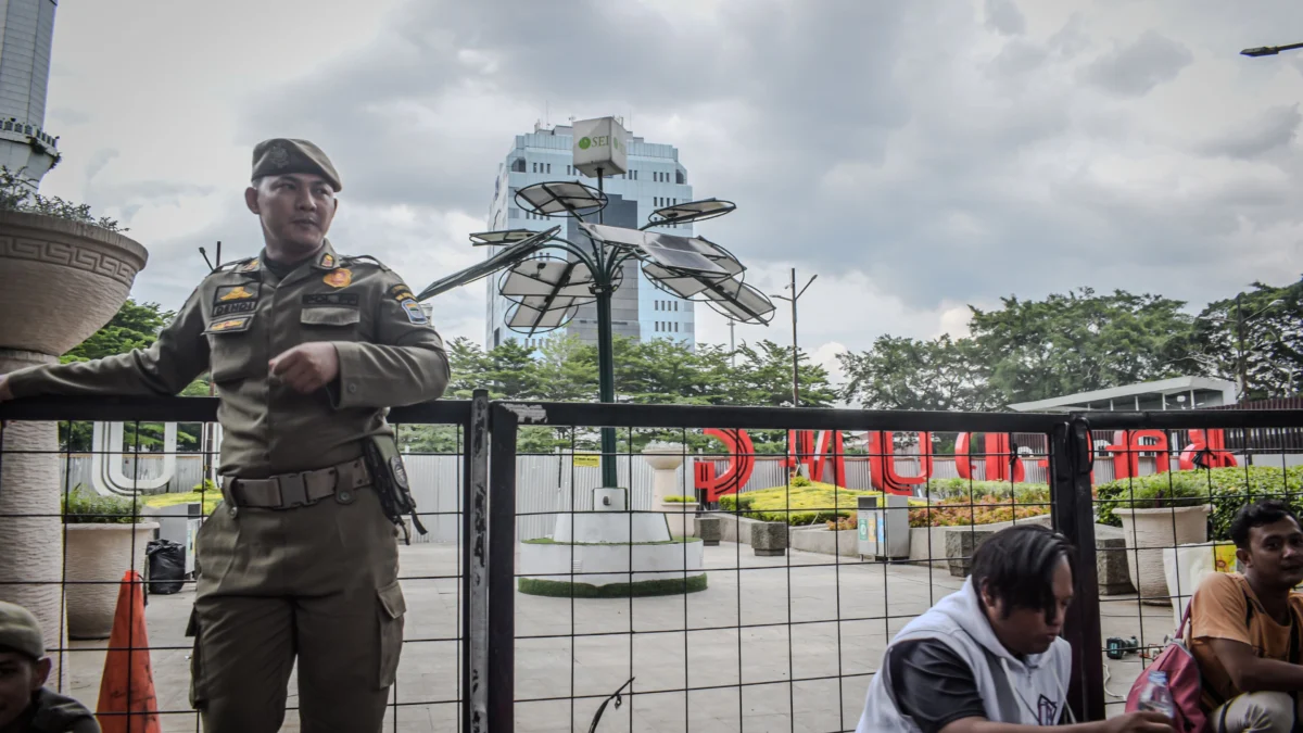 Petugas Satpol PP berjaga di sekitar Taman Alun-Alun Bandung, Kota Bandung, Jum'at (27/12). Pemerintah Kota (Pemkot) Bandung melakukan revitalisasi Alun-Alun Bandung dengan mengganti rumput sintetis yang ditargetkan rampung November, hingga saat ini belum diresmikan. Foto: Dimas Rachmatsyah / Jabar Ekspres