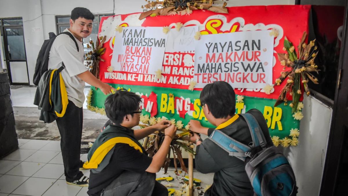 Sejumlah mahasiswa Universitas Bandung menempelkan poster tuntutan kepada pihak kampus di sebuah karangan bunga di Kampus Utama Universitas Bandung, Jalan Muararajeun, Kota Bandung, Senin (6/1). Foto: Dimas Rachmatsyah / Jabar Ekspres