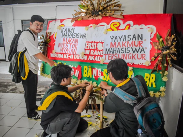 Sejumlah mahasiswa Universitas Bandung menempelkan poster tuntutan kepada pihak kampus di sebuah karangan bunga di Kampus Utama Universitas Bandung, Jalan Muararajeun, Kota Bandung, Senin (6/1). Foto: Dimas Rachmatsyah / Jabar Ekspres