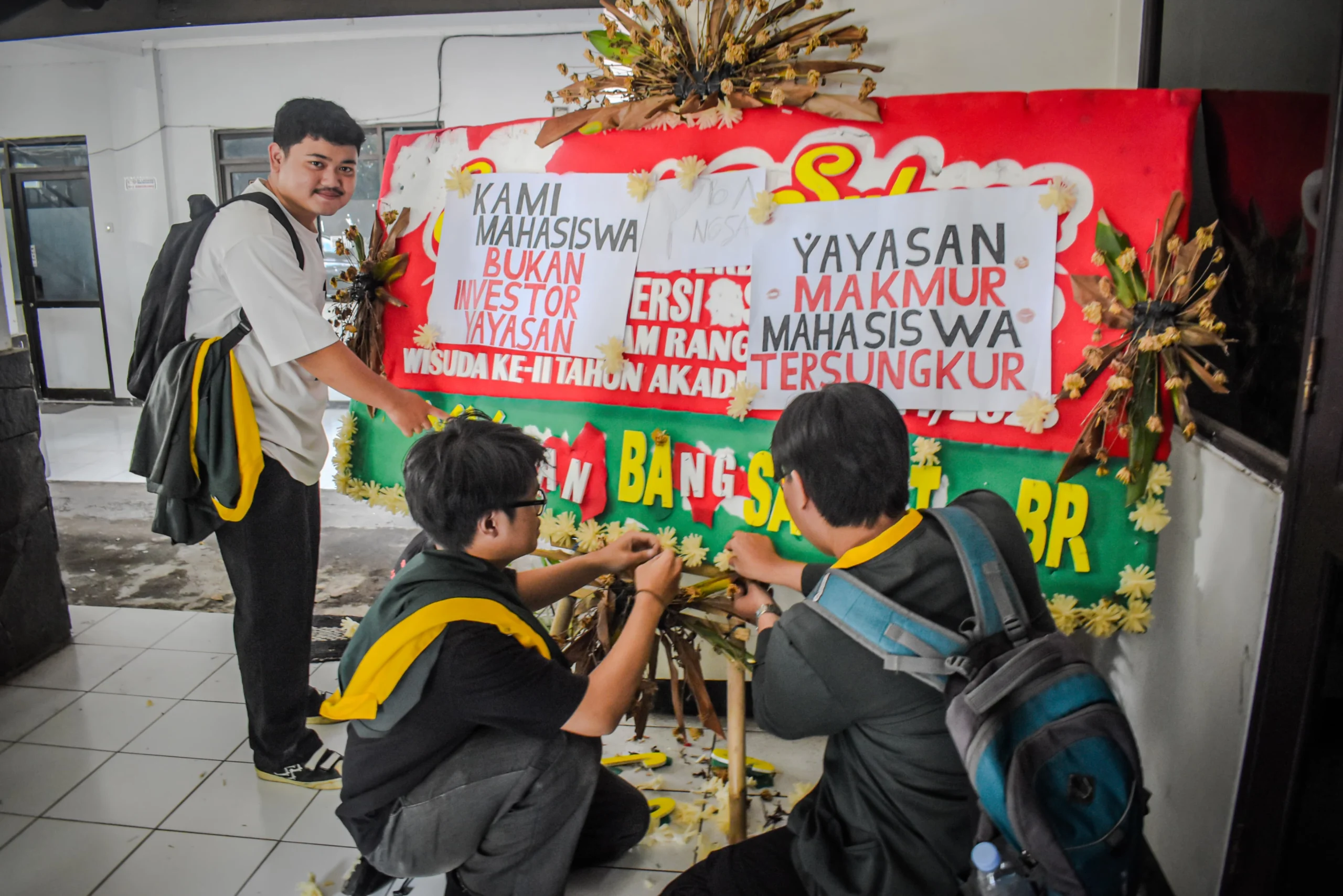 Sejumlah mahasiswa Universitas Bandung menempelkan poster tuntutan kepada pihak kampus di sebuah karangan bunga di Kampus Utama Universitas Bandung, Jalan Muararajeun, Kota Bandung, Senin (6/1). Foto: Dimas Rachmatsyah / Jabar Ekspres