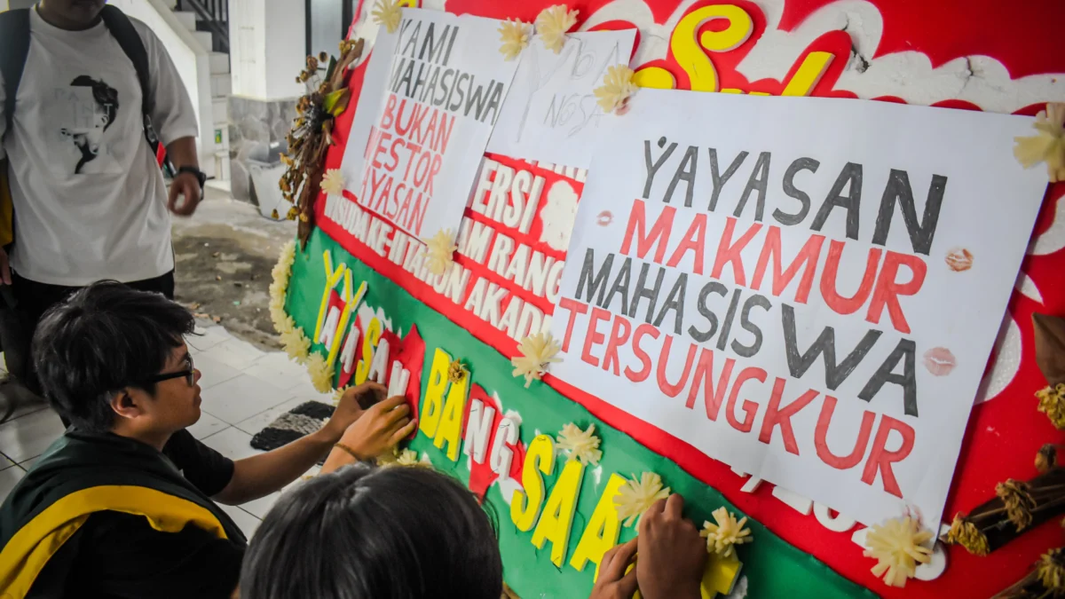 Sejumlah mahasiswa Universitas Bandung menempelkan poster tuntutan kepada pihak kampus di sebuah karangan bunga di Kampus Utama Universitas Bandung, Jalan Muararajeun, Kota Bandung, Senin (6/1). Foto: Dimas Rachmatsyah / Jabar Ekspres