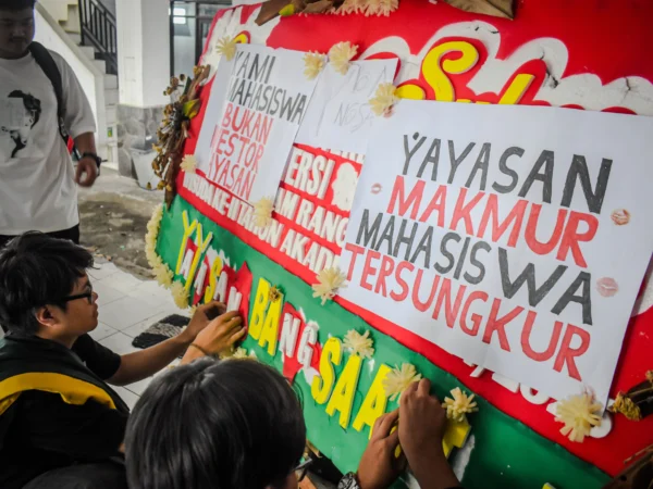 Sejumlah mahasiswa Universitas Bandung menempelkan poster tuntutan kepada pihak kampus di sebuah karangan bunga di Kampus Utama Universitas Bandung, Jalan Muararajeun, Kota Bandung, Senin (6/1). Foto: Dimas Rachmatsyah / Jabar Ekspres