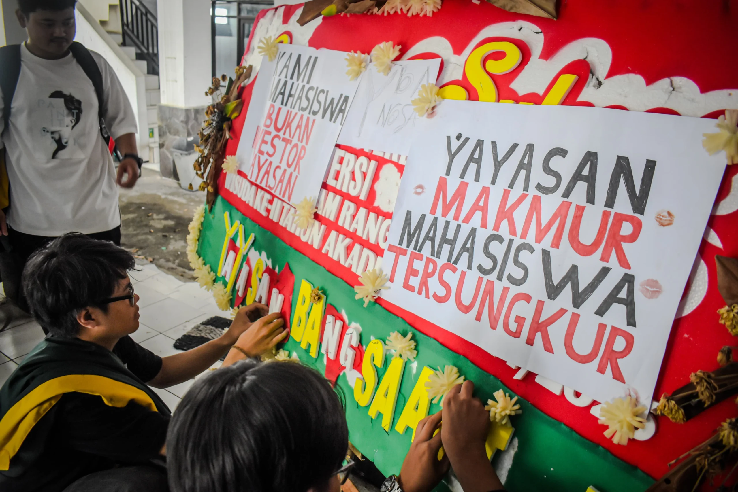 Sejumlah mahasiswa Universitas Bandung menempelkan poster tuntutan kepada pihak kampus di sebuah karangan bunga di Kampus Utama Universitas Bandung, Jalan Muararajeun, Kota Bandung, Senin (6/1). Foto: Dimas Rachmatsyah / Jabar Ekspres