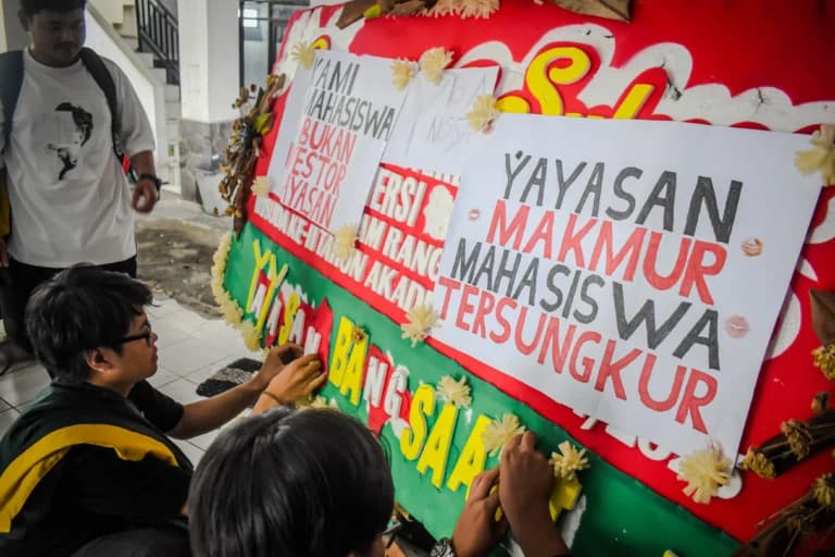 Ist. Sejumlah mahasiswa Universitas Bandung menempelkan poster tuntutan kepada pihak kampus di sebuah karangan bunga di Kampus Utama Universitas Bandung, Jalan Muararajeun, Kota Bandung, Senin (6/1). Foto: Dimas Rachmatsyah / Jabar Ekspres