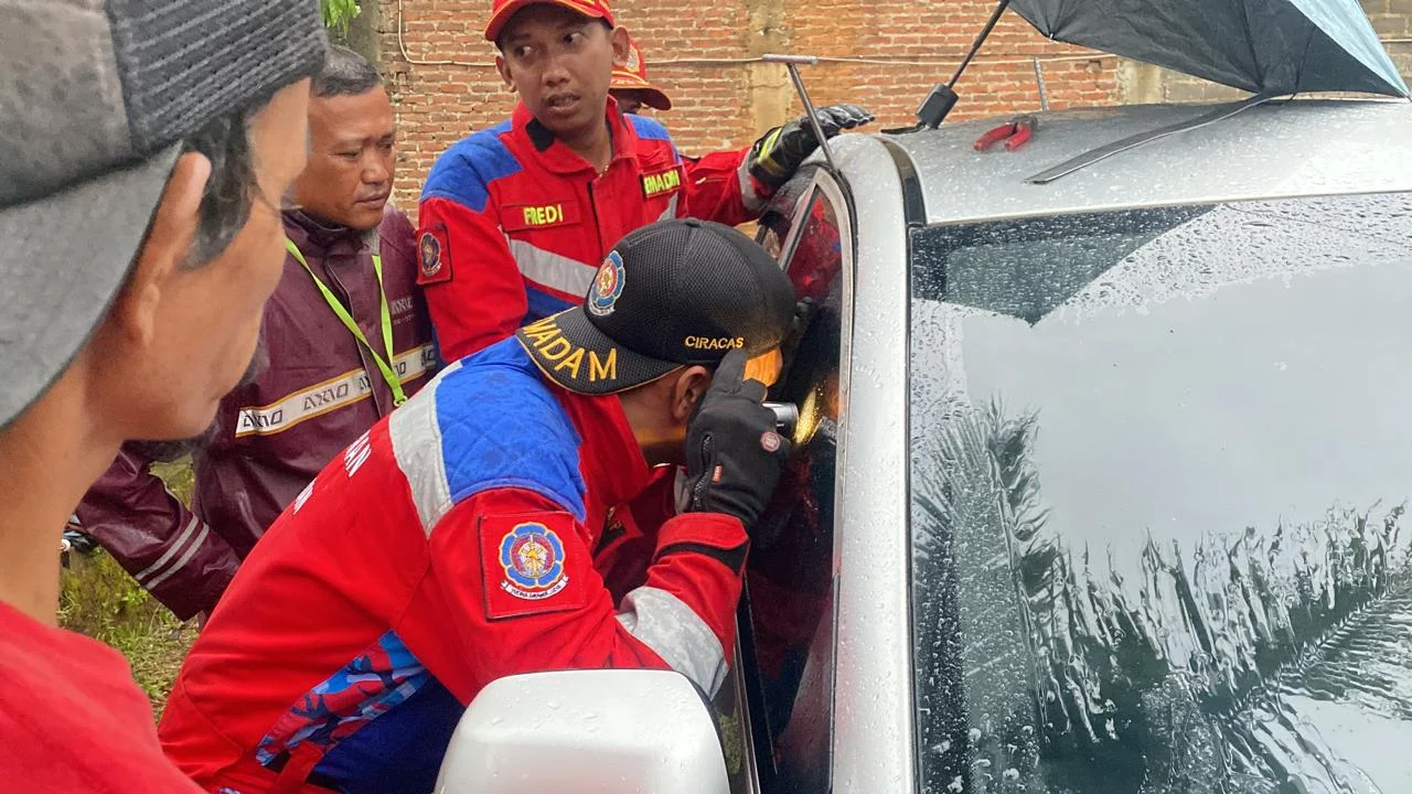 Tim Rescue Dinas Pemadam Kebakaran dan Penyelamatan Kabupaten Bandung dengan saat proses evakuasi anak usia 3 tahun yang terjebak di dalam mobil. (Disdamkar Kabupaten Bandung for Jabar Ekspres)