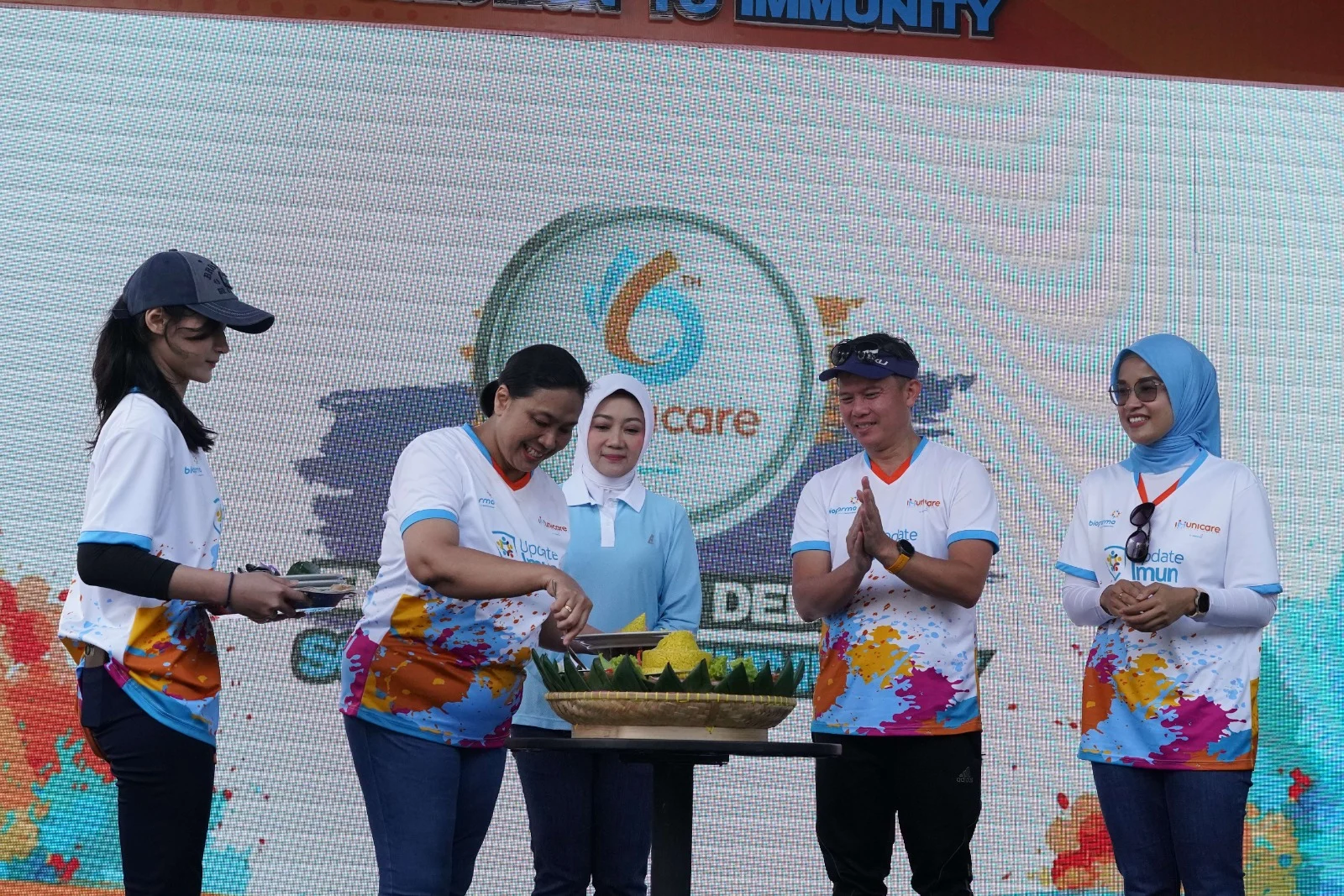 Direktur Medis & Hubungan Kelembagaan Bio Farma, Sri Harsi Teteki beserta Ketua Forum Jawa Barat Sehat, Atalia Praratya (tengah) di kegiatan pemotongan tumpeng pada acara Fun Run “Enam Tahun Dedikasi – Solution to Immunity” HUT Immunicare ke – 6