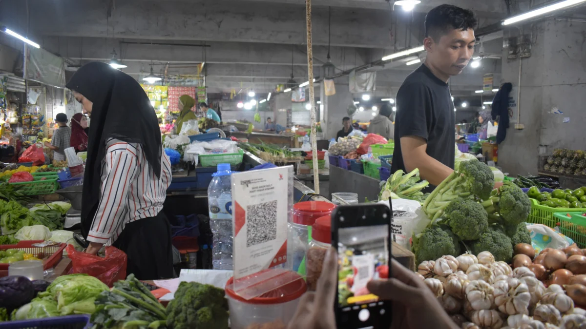 KEBUTUHAN PANGAN: Pembeli melakukan transaksi menggunakan QRIS di pasar Kosambi, Kota Bandung, Senin (10/2). Foto: Dimas Rachmatsyah