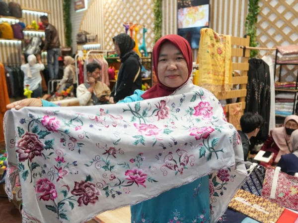 Salah satu karyawan Zahra Sulaman menunjukkan salah satu produk kain sulaman khas Bukittinggi untuk bahan kebaya di Inacraft 2025