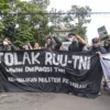 Ilustrasi Massa aksi membentangkan tulisan berisi protes, menolak UU TNI di depan Gedung DPRD Jabar, Bandung, Kamis (20/3). Foto: Dimas / Jabar Ekspres