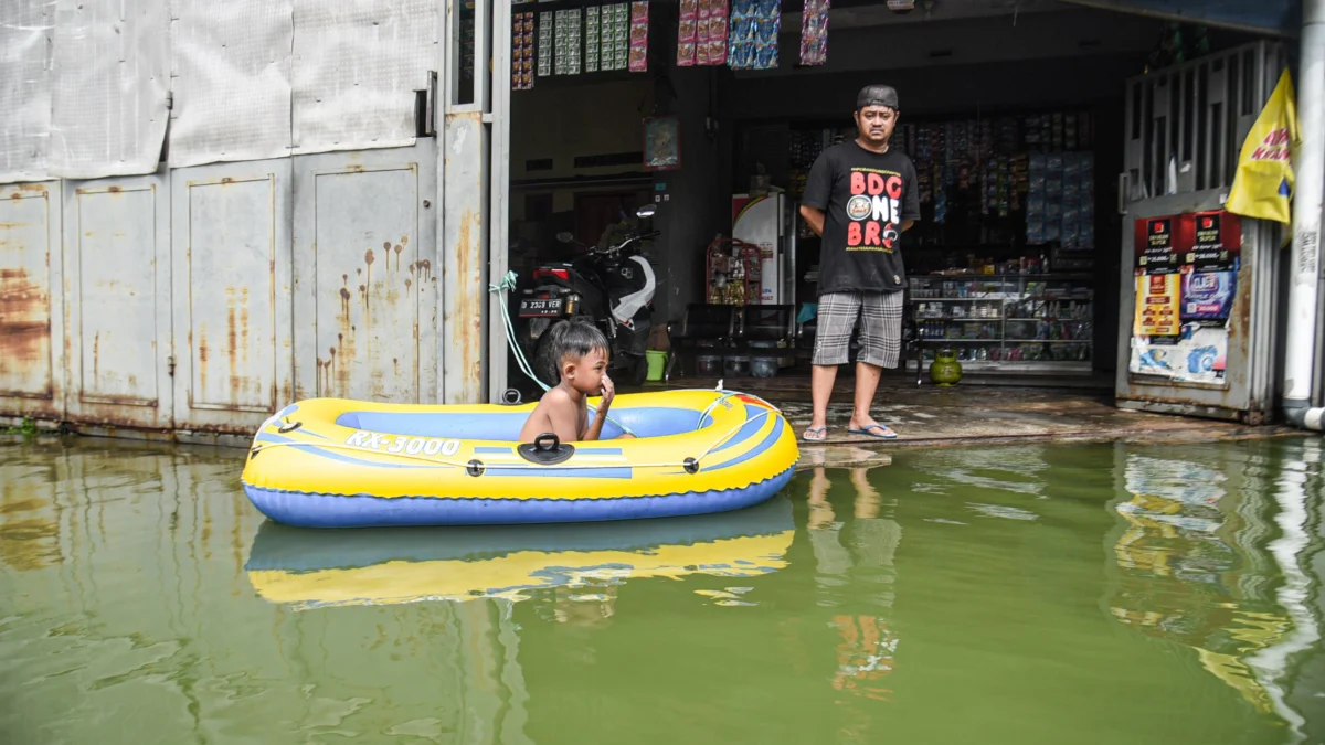 Seorang anak bermain di depan rumahnya yang terendam banjir di Kampung Cijagra, Bojongsoang, Kabupaten Bandung, Minggu (9/3). Foto: Dimas Rachmatsyah / Jabar Ekspres