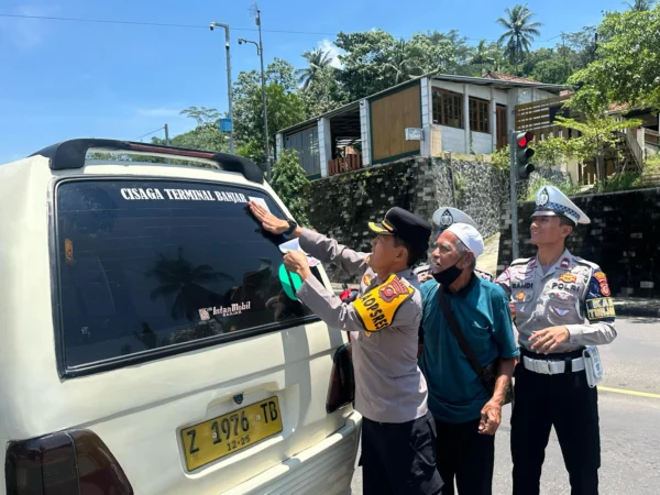 Waka Polres Banjar Kompol Dani Prasetya memasang stiker di kaca belakang angkutan kota, Kamis (13/3/2025). (Cecep Herdi/Jabar Ekspres)