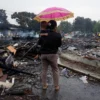 Seorang ibu menggendong anaknya melihat puing sisa kebakaran bangunan di kawasan Sukahaji, Babakan Ciparay, Kota Bandung, Kamis (10/4). Foto: Dimas Rachmatsyah / Jabar Ekspres