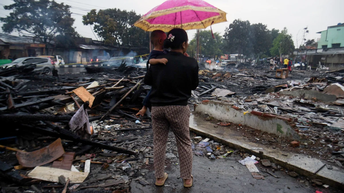 Seorang ibu menggendong anaknya melihat puing sisa kebakaran bangunan di kawasan Sukahaji, Babakan Ciparay, Kota Bandung, Kamis (10/4). Foto: Dimas Rachmatsyah / Jabar Ekspres