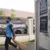 Petugas kebersihan berjalan di samping poster perlawanan di depan SMA Negeri 1, Kota Bandung, Senin (21/4). Foto: Dimas Rachmatsyah / Jabar Ekspres