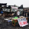 Sejumlah warga berada ditengah puing sisa kebakaran bangunan dan spanduk "Sukahaji Melawan" di kawasan Sukahaji, Babakan Ciparay, Kota Bandung, Kamis (10/4). Foto: Dimas Rachmatsyah / Jabar Ekspres