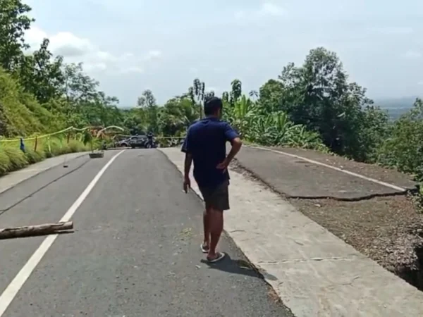 Seorang warga berada di lokasi pergeseran tanah yang menyebabkan bahu Jalan Angsana Gunung Kelir di Desa Neglasari, Kecamatan Pamarican, Kabupaten Ciamis, longsor, Minggu (20/4/2025). (Cecep Herdi/Jabar Ekspres)